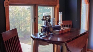Un comedor con una mesa y sillas de madera, un amplio ventanal de arco y vistas a árboles.
