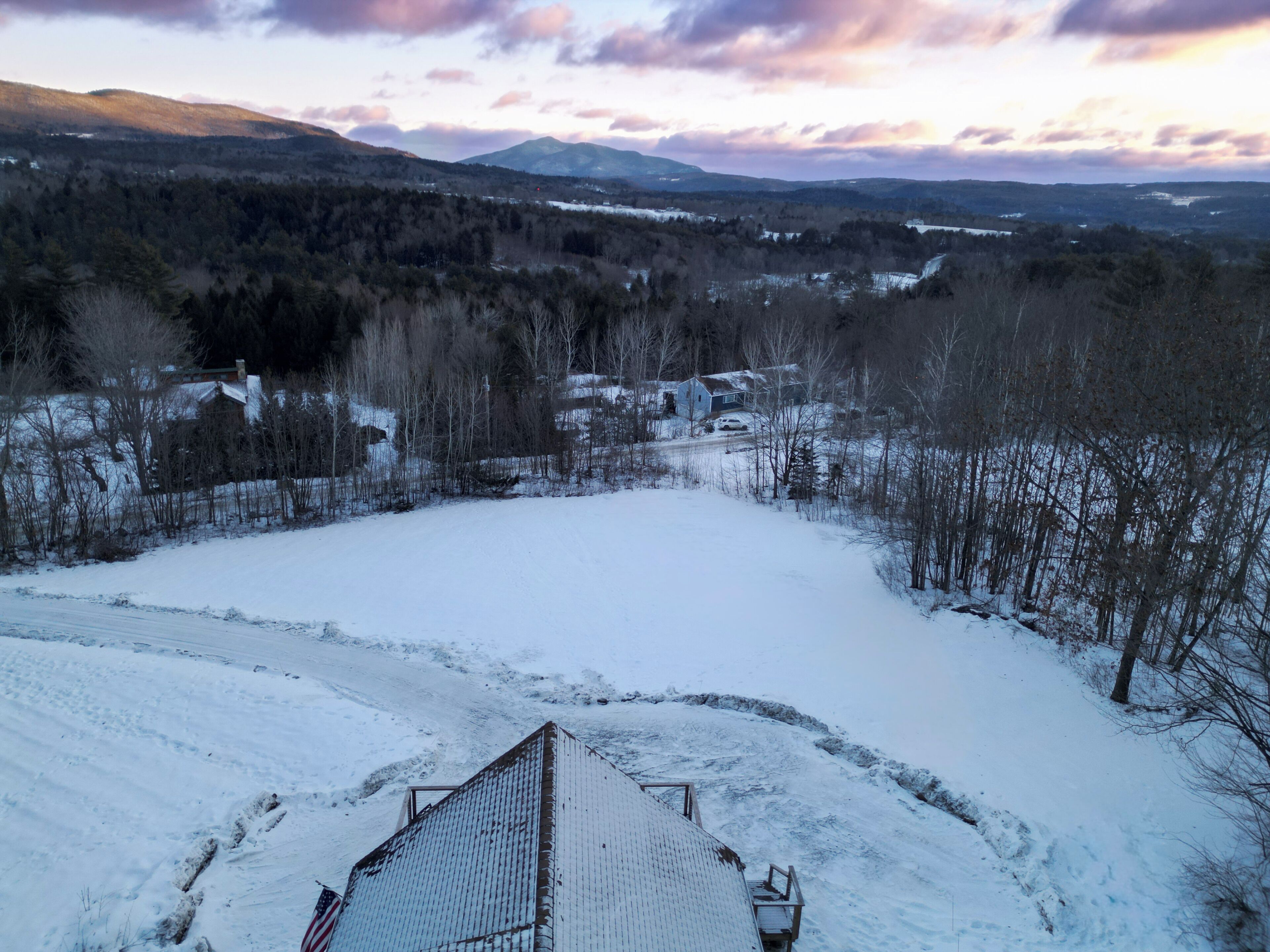 Schneebedeckte Landschaft mit einem Haus und einer Metallkonstruktion im Vordergrund.