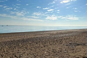 Uma praia com céu claro e mar calmo.