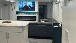 A modern kitchen with a built-in TV, a ceiling fan, and a fish tank.