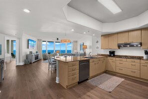 A modern kitchen with wooden cabinets, a central island, and a view to the outside.