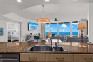 A modern kitchen with a granite countertop, stainless steel sink, and wooden cabinets.