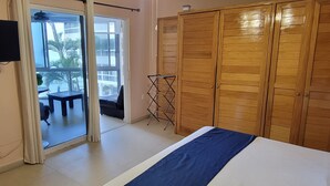 Ein Schlafzimmer mit einem Bett, einem an der Wand befestigten Fernseher, einem Holzschrank und einem Balkon mit Tisch und Stühlen.