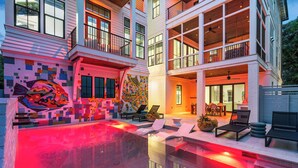 Une maison moderne dotée d’une piscine, d’un espace extérieur aménagé et d’un mur décoré d’une mosaïque colorée.
