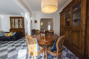 A dining area with a round wooden table, four chairs, a chandelier, and a checkered floor.
