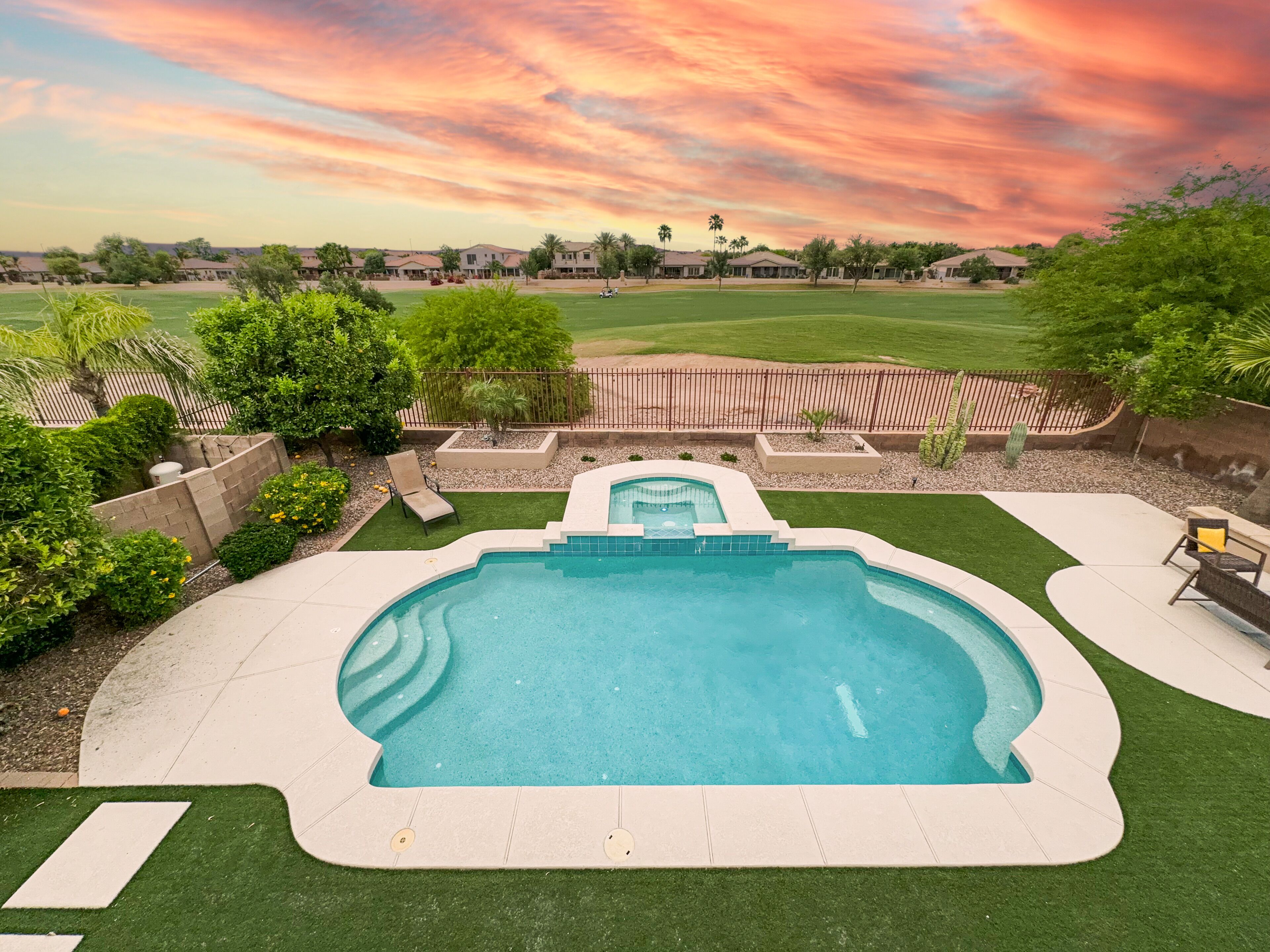 A backyard with a swimming pool, a patio area, and a view of a residential neighborhood.
