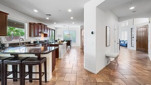Una cocina amplia con una isla grande, armarios de madera oscura y vista a un comedor.