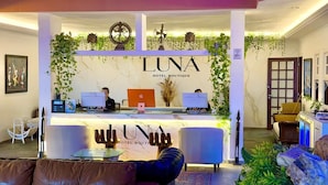 A hotel reception area with a reception desk, two computers, and a receptionist. - LUNA Hotel Boutique (Guarujá)