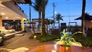 An outdoor seating area with a wooden table, chairs, and potted plants. - LUNA Hotel Boutique (Guarujá)