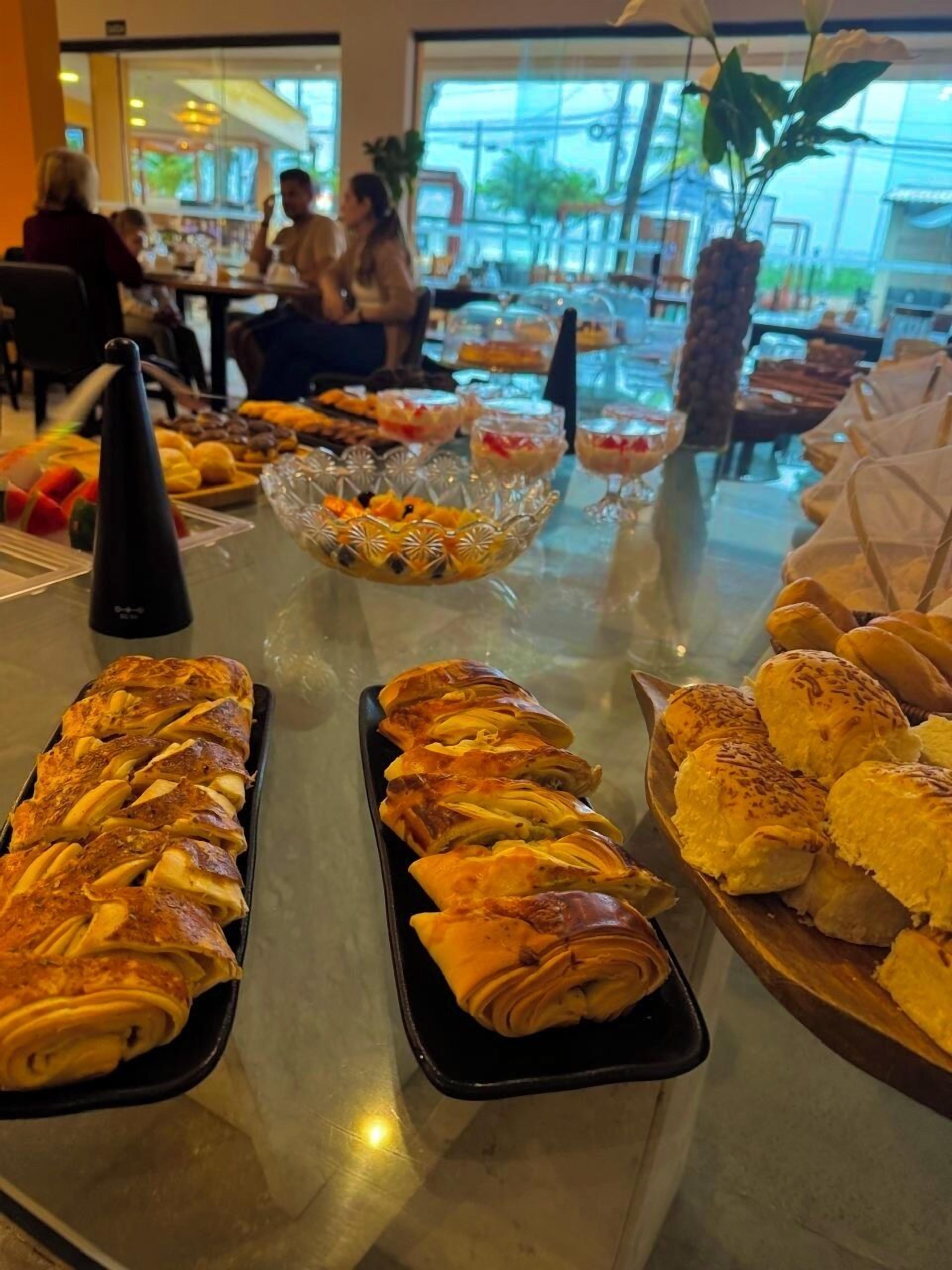 Un bufé con diversas opciones de panadería y cuencos de fruta.