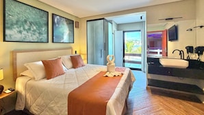 A hotel room with a bed, a bathroom with a sink, and a balcony with a view. - LUNA Hotel Boutique (Guarujá)