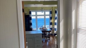 Una cocina con vista al océano, suelo de madera y un comedor con mesa y sillas.