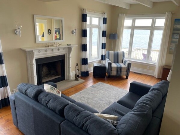 Ein Wohnzimmer mit Kamin, einem gestreiften Sessel und einer Couch.