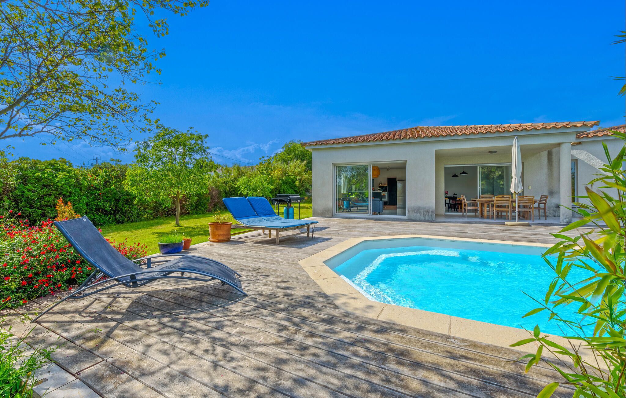 A modern house with a swimming pool, outdoor furniture, and a garden.