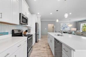 Una cocina moderna con armarios blancos, electrodomésticos de acero inoxidable y piso de madera.