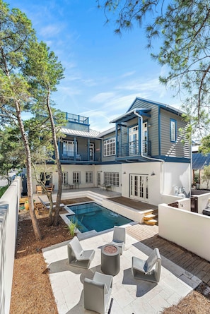 A two-story house with a swimming pool, outdoor seating, and a covered patio area. - Wave Jumper | Cottage in Rosemary Beach with Access to Rosemary Beach, Pools, Tennis, and Gym (Rosemary Beach)