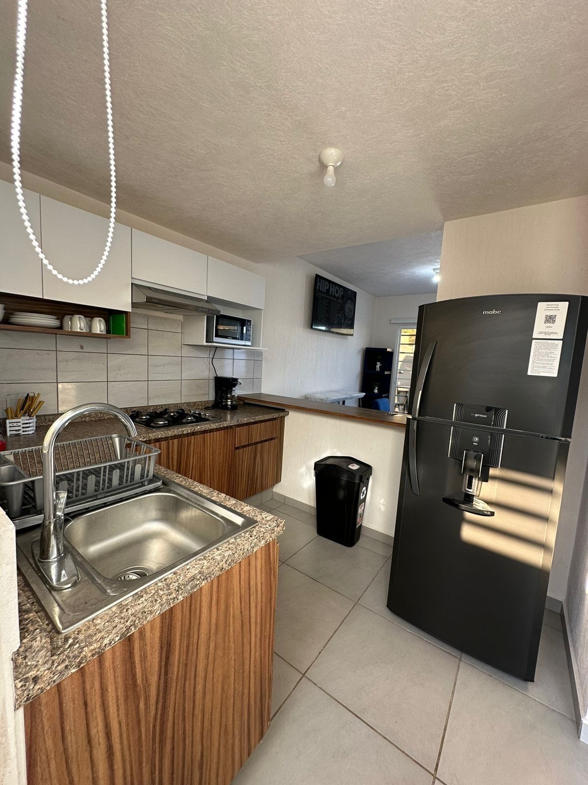 A modern kitchen with a stainless steel sink, a black refrigerator, and a microwave.