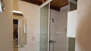 Une salle de bain moderne avec une douche à parois de verre, un lavabo blanc et un plafond en bois.