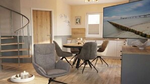 Un salón moderno con un sillón gris, una mesa de centro redonda y un televisor de pantalla plana mostrando una escena de playa.