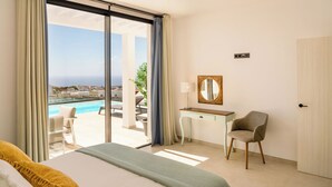 A hotel room with a bed, a desk, a chair, a large window with a view of the sea, and a door. - CAPRICA by Buenavilla| Indulge in Serene Opulence at Las Breñas, Lanzarote. (Las Breñas)