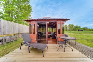 Una terraza de madera con mobiliario exterior, un área de descanso cubierta y vistas a un campo de césped.