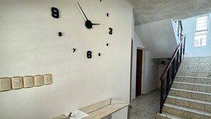 Un couloir avec une grande horloge murale, un banc et un escalier.
