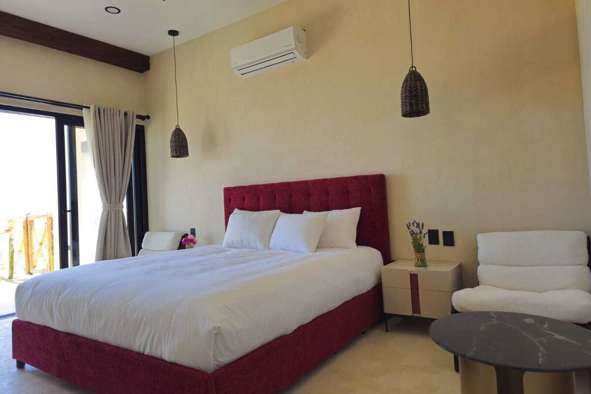 A bedroom with a large bed, a nightstand, a chair, and a small table.