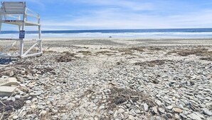 Een strand met een redderpost en een bord met de tekst om afval op te ruimen.