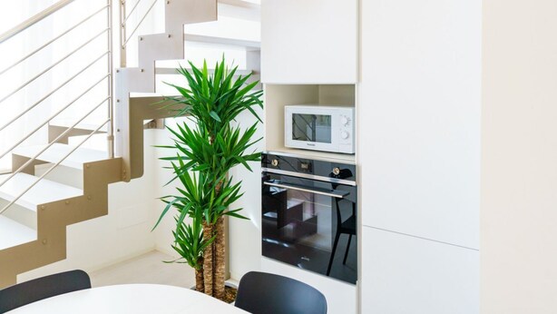 A modern kitchen with built-in appliances, a staircase, and a dining area. - Corte Farina - Modern and central residence (Verona)
