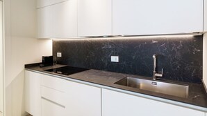 A modern kitchen with white cabinets, a black marble backsplash, and stainless steel appliances. - Corte Farina - Modern and central residence (Verona)
