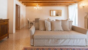 A cozy room with a sofa, a wooden cabinet, a chandelier, and a mirror on the wall. - Fabulous residence overlooking Piazza Erbe (Verona)