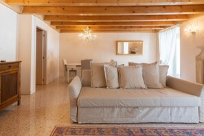 A cozy room with a sofa, a wooden cabinet, a chandelier, and a mirror on the wall. - Fabulous residence overlooking Piazza Erbe (Verona)