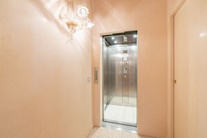 An elevator with a control panel, a light fixture, and a door. - Fabulous residence overlooking Piazza Erbe (Verona)