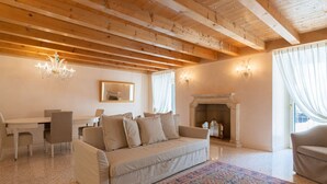 A cozy living room with a sofa, a dining table, chairs, a chandelier, a fireplace, and a patterned rug. - Fabulous residence overlooking Piazza Erbe (Verona)