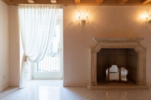 A room with a fireplace, a window with curtains, and a wall-mounted light fixture. - Fabulous residence overlooking Piazza Erbe (Verona)