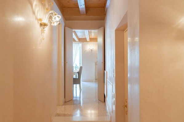 A hallway with a chandelier, a dining area in the background, and a door on the right. - Fabulous residence overlooking Piazza Erbe (Verona)