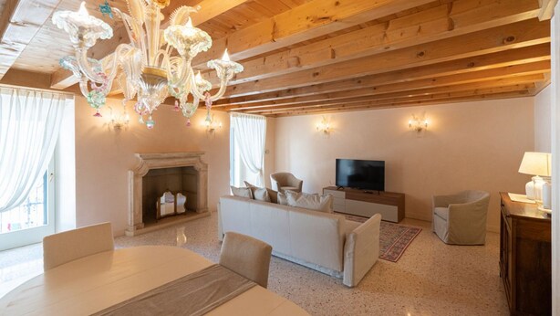A living room with a fireplace, a television, a sofa, and a dining table. - Fabulous residence overlooking Piazza Erbe (Verona)