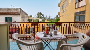 A balcony with a table set for two, chairs, and a bottle of juice.