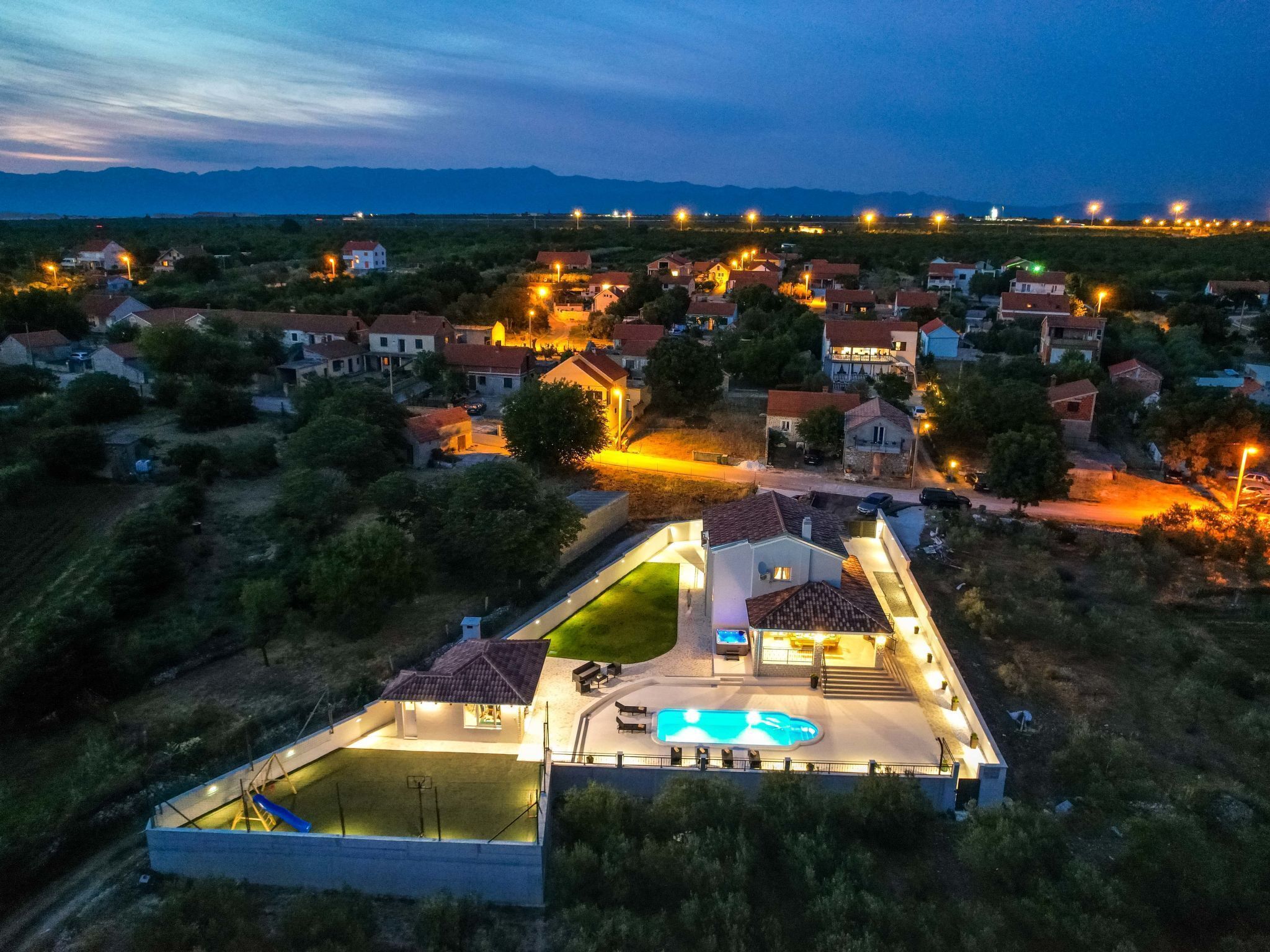 A residential area with houses, a swimming pool, and a well-lit patio area.