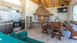 A modern kitchen with a stone wall, wooden ceiling beams, and a fireplace. - Villa Šime by Interhome (Zadar/Sukošan)