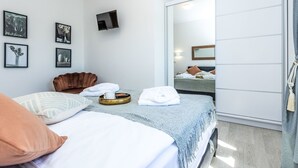 A modern hotel room with a bed, a brown leather chair, a flat-screen TV, and a sliding door closet. - Villa Šime by Interhome (Zadar/Sukošan)