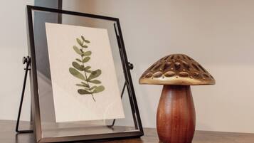 A framed botanical print on a stand next to a wooden mushroom-shaped lamp.