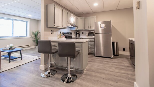 Een moderne keuken met een centraal eiland, roestvrijstalen apparatuur en een raam met zonwering.