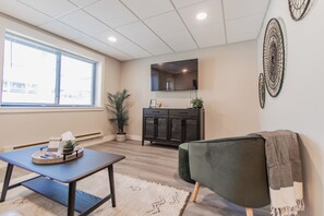 Un salon moderne avec un canapé, une table basse, un meuble et une grande fenêtre.