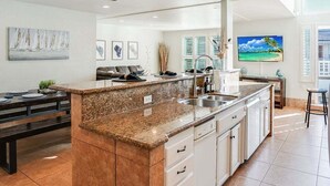 A modern kitchen with a granite countertop, white cabinetry, and a large island. - Massive Beach Home | Ocean View | Amazing Rooftop (San Diego)