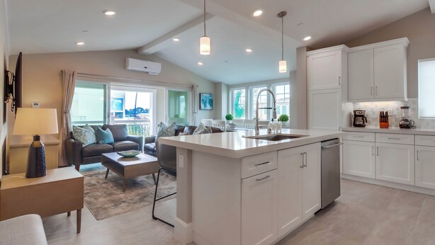 A modern kitchen with white cabinets, a central island, and pendant lighting. - Steps to Water - Newly Built Bayside Dream | Patios, Fire Pit, Bay Views, Garage (San Diego)