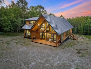 A cabin with a sloped roof, large windows, and a wooden deck.