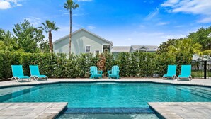 A swimming pool with turquoise chairs, surrounded by greenery and a building in the background. - Villa Miramar | Luxury 7-Bedroom Villa at Reunion Resort (Kissimmee)