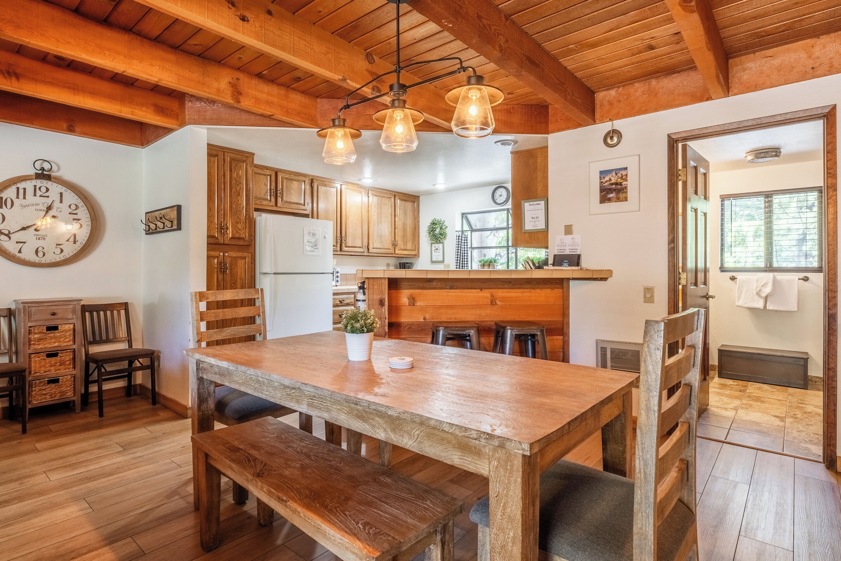 Une cuisine rustique avec des meubles de rangement en bois, une table à manger en bois et des luminaires suspendus.