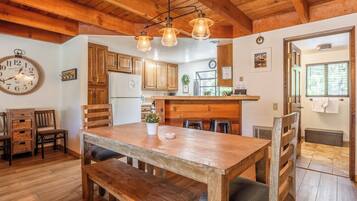 Une cuisine rustique avec des meubles de rangement en bois, une table à manger en bois et des luminaires suspendus.